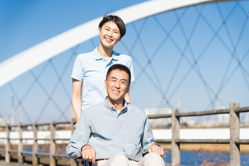車椅子を押して散策する男性と介護士