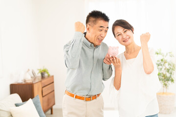 豚の貯金箱を持つ熟年夫婦