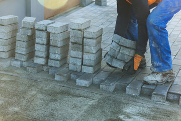 Worker carefully place concrete blocks on new pavement, showcasing their teamwork construction...