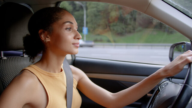 Cheerful African American woman female girl businesswoman business car auto automobile vehicle transportation driver driving ride road travel trip smiling steering traffic driveway rent service owner