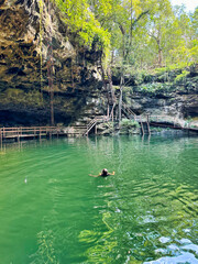 Visitors enjoy a swim in the cool waters of the X’Canche Cenote, a natural limestone cavern with a deep natural pool of fresh water near Ek Balam,near Valladolid,Yucatan,Mexico