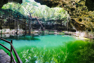 Wooden walkway around the famous X'Canche cenote, with a natural pool of fresh water in a limestone...