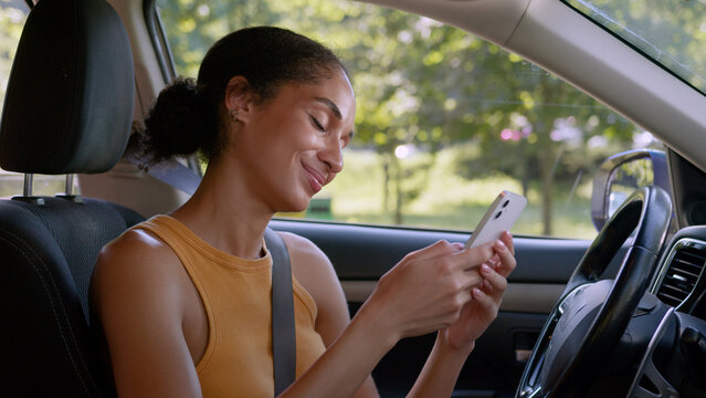African American woman looking screen mobile phone smartphone cellphone smiling enjoyment online social media device female driver car transport automobile auto vehicle girl businesswoman business web