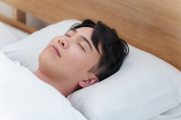 朝ベッドで寝る男性