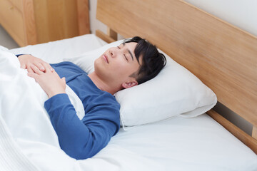 朝ベッドで寝る男性