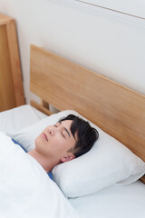 朝ベッドで寝る男性