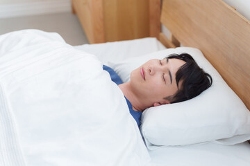 朝ベッドで寝る男性