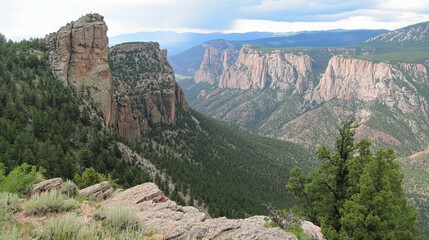 Panoramic view of a vast canyon landscape, featuring towering rock formations, lush green vegetation, and a hazy sky