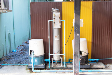 Old water filter tank and water pump system structure on zinc wall sheet background. Site...