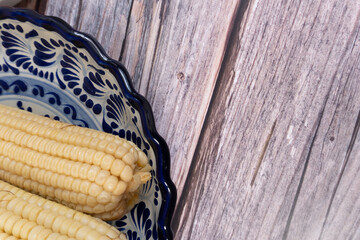 Close-up of a plate of cooked corn on the cob, ready to be prepared, with space for text. Mexican...