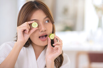 Beautiful Asian woman shows off cucumber slices to nourish her skin regularly, nourishing your skin with natural ingredients
