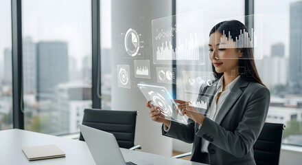 Young businesswoman analyzing data on a futuristic device, Asian professional reviewing business insights with advanced technology
