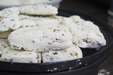Fresh cheese blocks with herbs on display at market