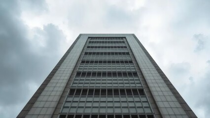 Obraz premium Dramatic Low Angle of Modern Architecture Building Under Cloudy Sky