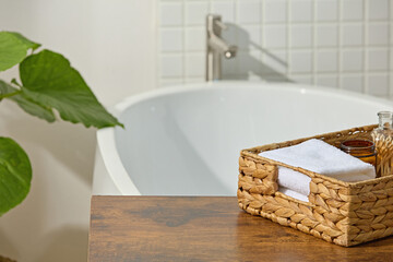 Clean white bathtub against mosaic wall with rattan tray and folded towel. A bright, natural...