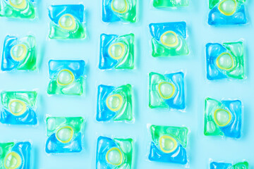Pattern of multicolored capsules with liquid washing powder on a blue background from above close-up.