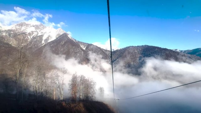 Gondola ascends above forested slopes and clouds in Tufandag Mountains. Gabala, Azerbaijan