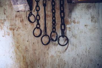 Group of rusty metal shackles (or handcuff) hanging on the wall. A shackle is a restraint, either...