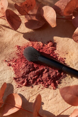 Blush Brush with Red Powder on Rustic Surface Surrounded by Fall Leaves, Beauty Still Life