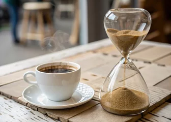 Fototapeten Time slipping away with a cup of steaming coffee resting on a wooden table © ardianion
