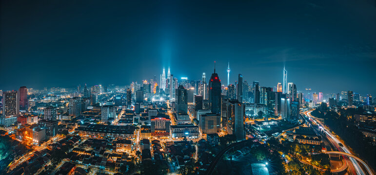 Stunning Night Panoramic View of Kuala Lumpur City Skyline with Illuminated Skyscrapers and Light Trails.