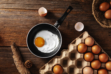 Fresh Egg in Frying Pan on Rustic Wooden Table with Eggs Nearby