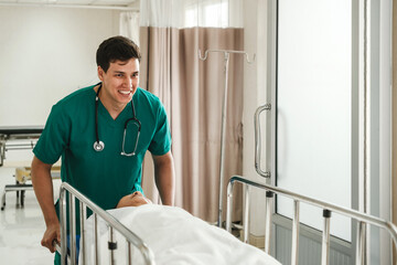 Young male nurse in green scrubs urgently wheels a patient on a stretcher into the emergency room....