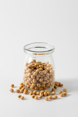 Glass jar filled with light brown soybeans on a white background