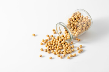 Spilled Yellow Soybeans from Glass Container on White Background