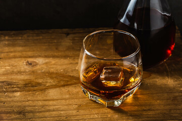 Classic Whiskey Glass with Ice and Decanter on a Wooden Table