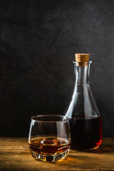Elegant Glass and Bottle of Whiskey on Wooden Table with Dark Background
