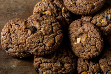 Freshly Baked Chocolate Cookies with Nuts and Raisins on Wooden Plate