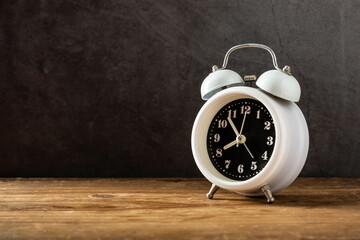 Vintage Alarm Clock on Wooden Table Against Dark Background