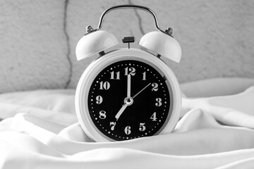 Classic White Alarm Clock on Soft White Fabric Background