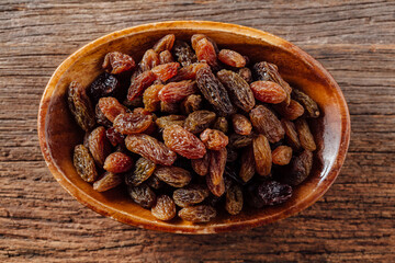 Bowl of assorted dried raisins on wooden table background