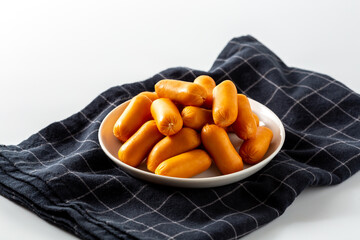 Fresh Mini Sausages on a Plate with a Black Checkered Cloth