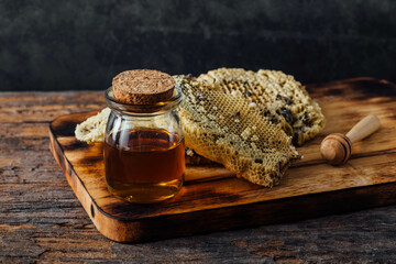 Natural Honey in Jar with Honeycomb on Wooden Board Background