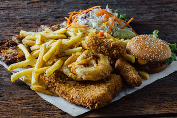 Crispy Fried Chicken, French Fries, Salad, and Burger on Wooden Table