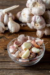 Fresh Garlic Bulbs and Cloves in a Glass Bowl on Rustic Wood Surface