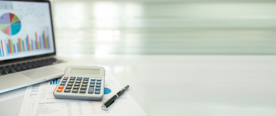 calculator, business report and financial portfolio show on screen laptop computer. with review of...