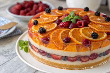  shows a layered dessert with slices of orange and berries, topped with more fruit and a sprig of mint. In the background, there's a bowl of raspberries.