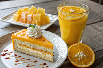 shows a slice of orange cake with whipped cream and caramel sauce on a plate, accompanied by a glass of orange juice with a slice of orange and a plate of diced oranges in the background.