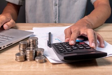 A businessman at his desk. A man with laptop, calculator, paperwork, and coins in office.