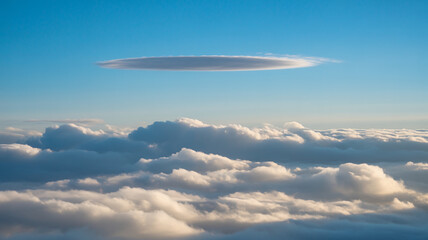 A lenticular cloud hovers above a sea of cumulus clouds in a bright blue sky