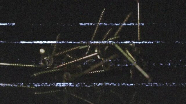 Screws appearing at top forming pile on shiny surface, glitch lines drifting simulating assembly