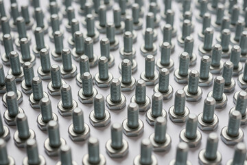 A large group of shiny metal bolts are arranged in a uniform pattern, isolated on white background