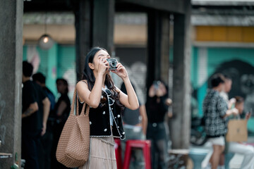 Young tourist taking pictures in a traditional asian market with vintage camera