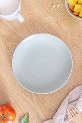 A close-up of an empty light green plate on a wooden table.