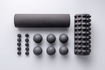Assorted black foam rollers and massage balls arranged on a light background for fitness recovery