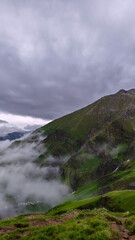 Misty Highland Valley with Lush Slopes and Cloud-Covered Mountain Peaks